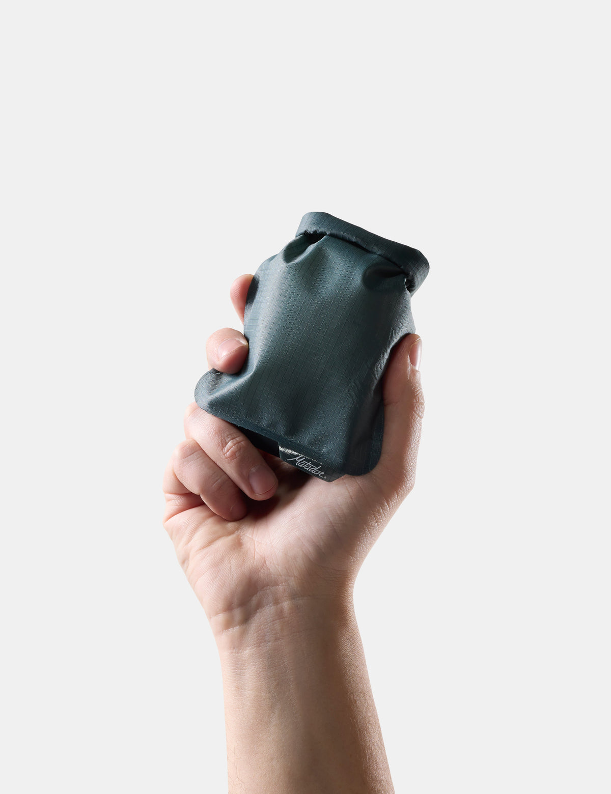 Hand holding a compact Matador FlatPak Soap Bar Case in Juniper green color