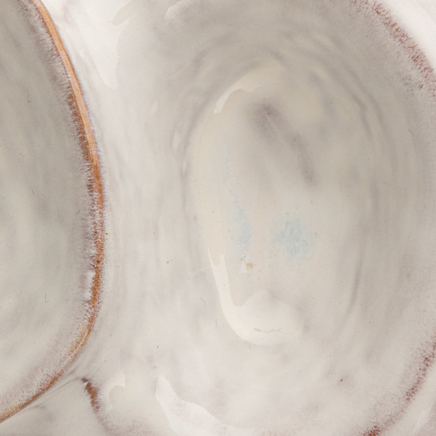 Close-up interior detail of white glazed stoneware pedestal bowl with rustic rim