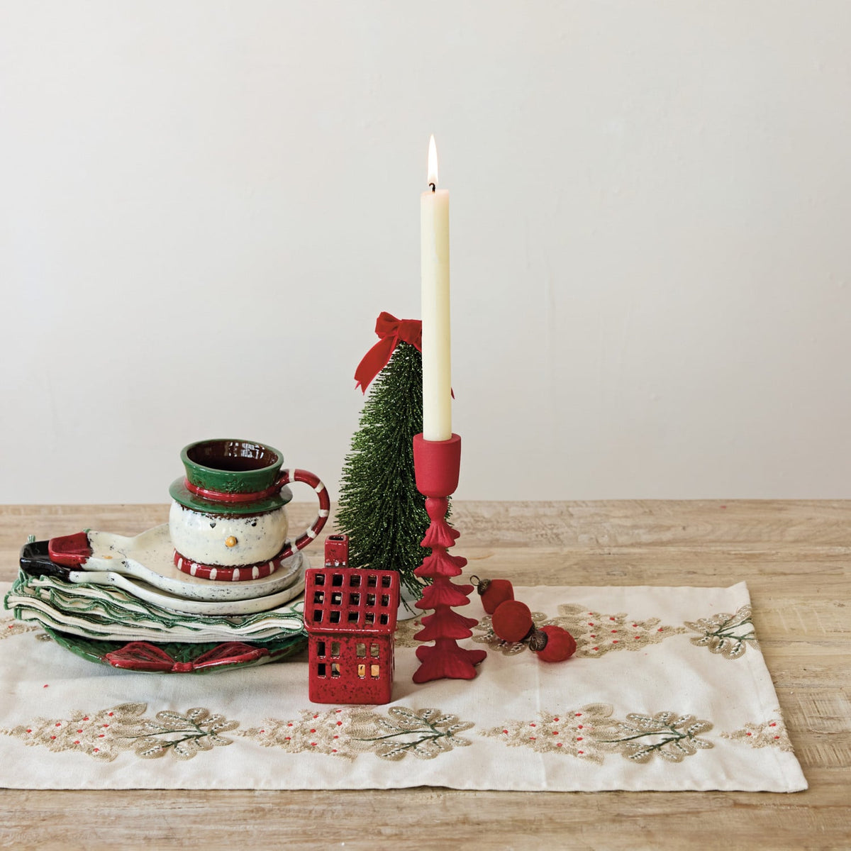 Cotton table runner with mistletoe embroidery styled with Christmas tableware and candle on wood surface