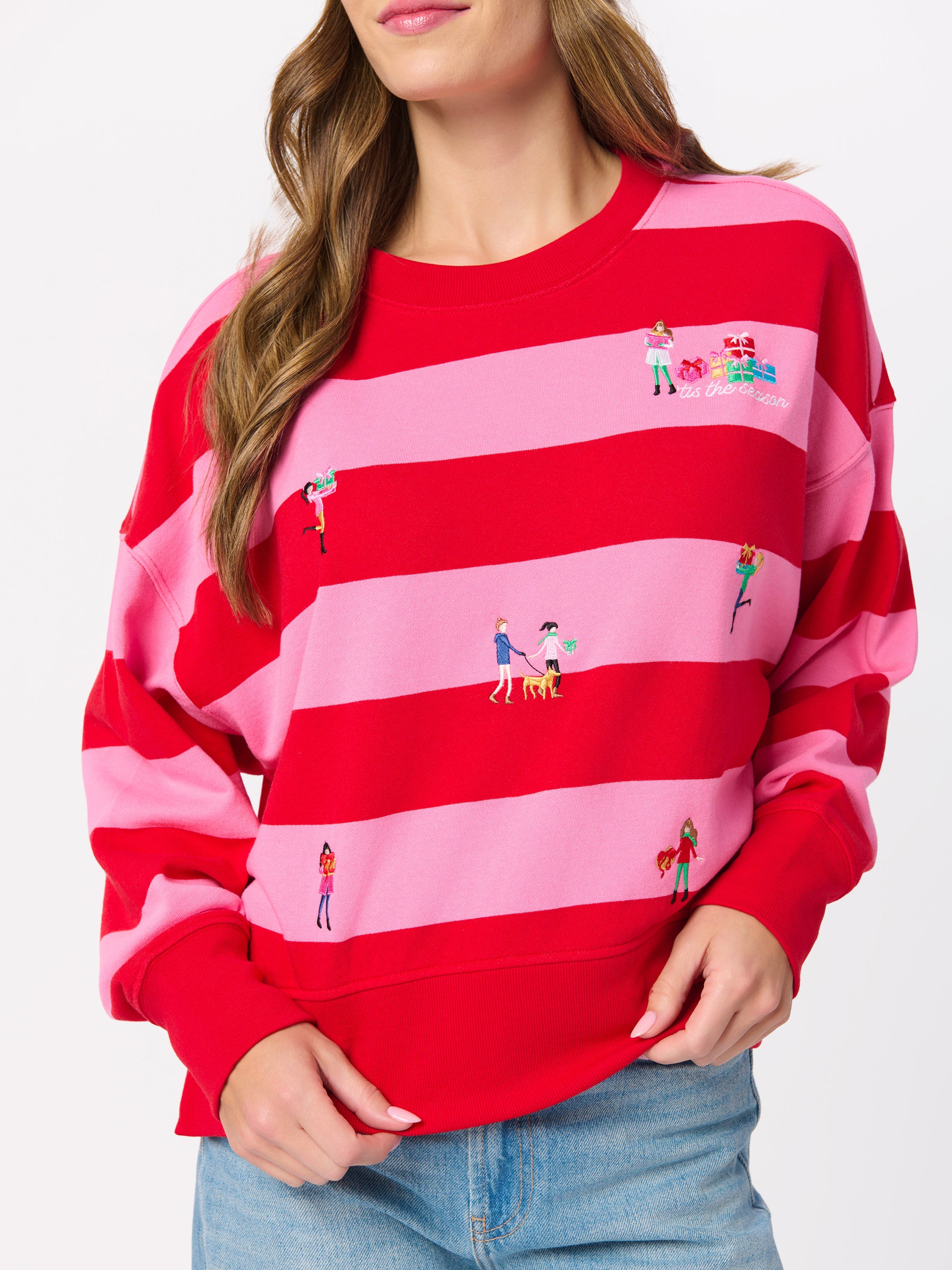 Model wearing red and pink striped sweatshirt with small embroidered holiday figures throughout