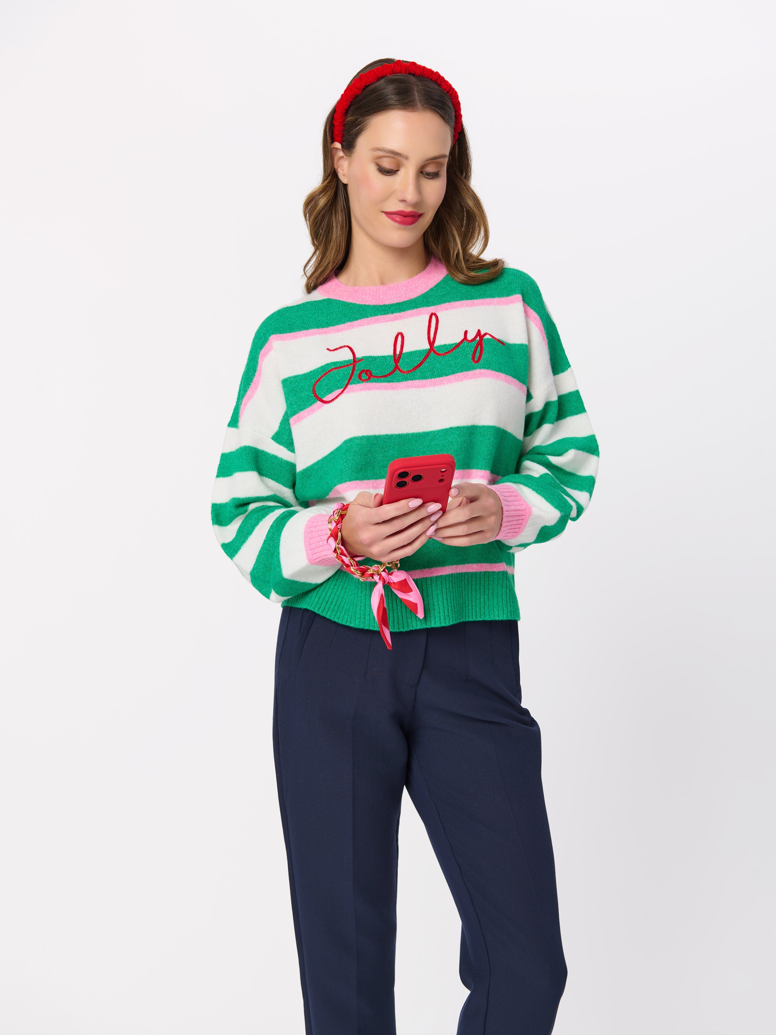 Model wearing green and white striped Jolly knit sweater with pink accents and red script lettering