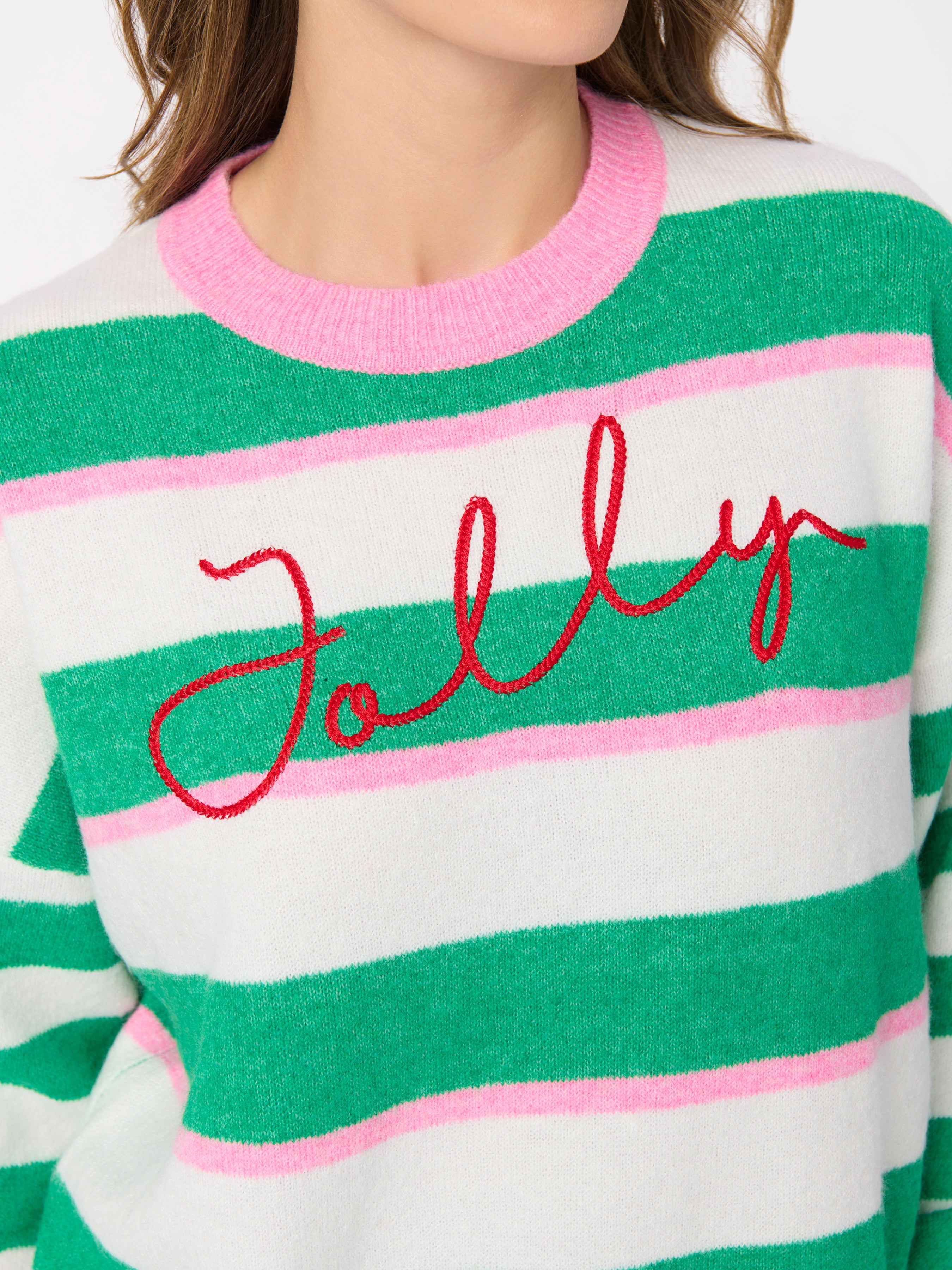 Close-up detail of green and pink striped sweater with red Jolly script embroidery