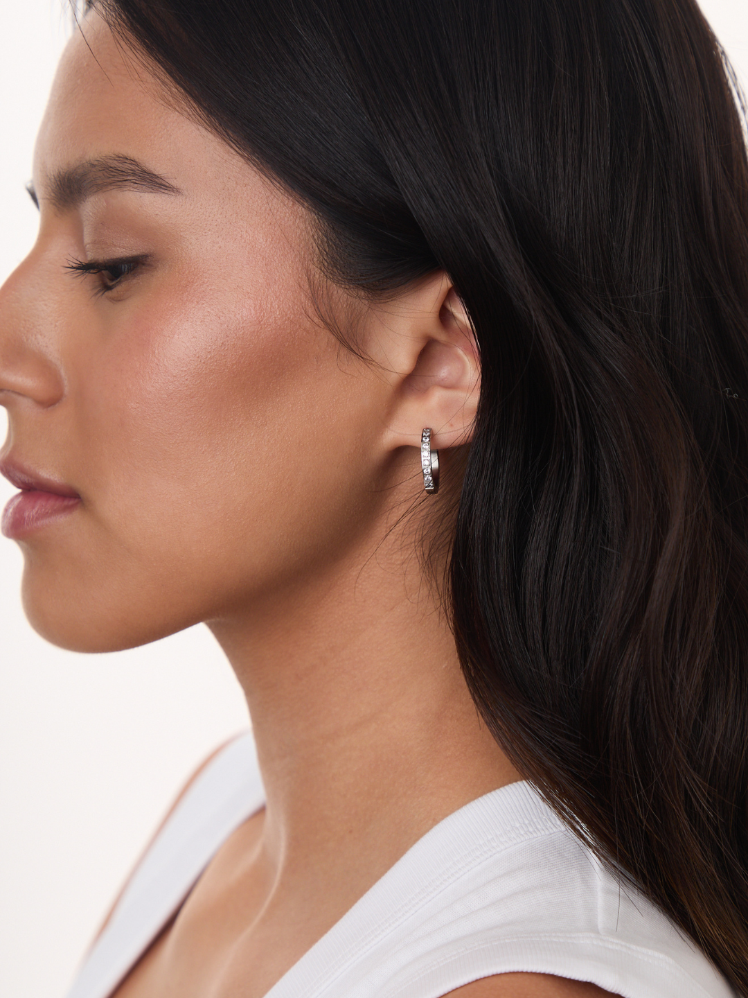 Model wearing Jay Huggies Pave silver hoop earrings with pavé crystal detailing, side profile view