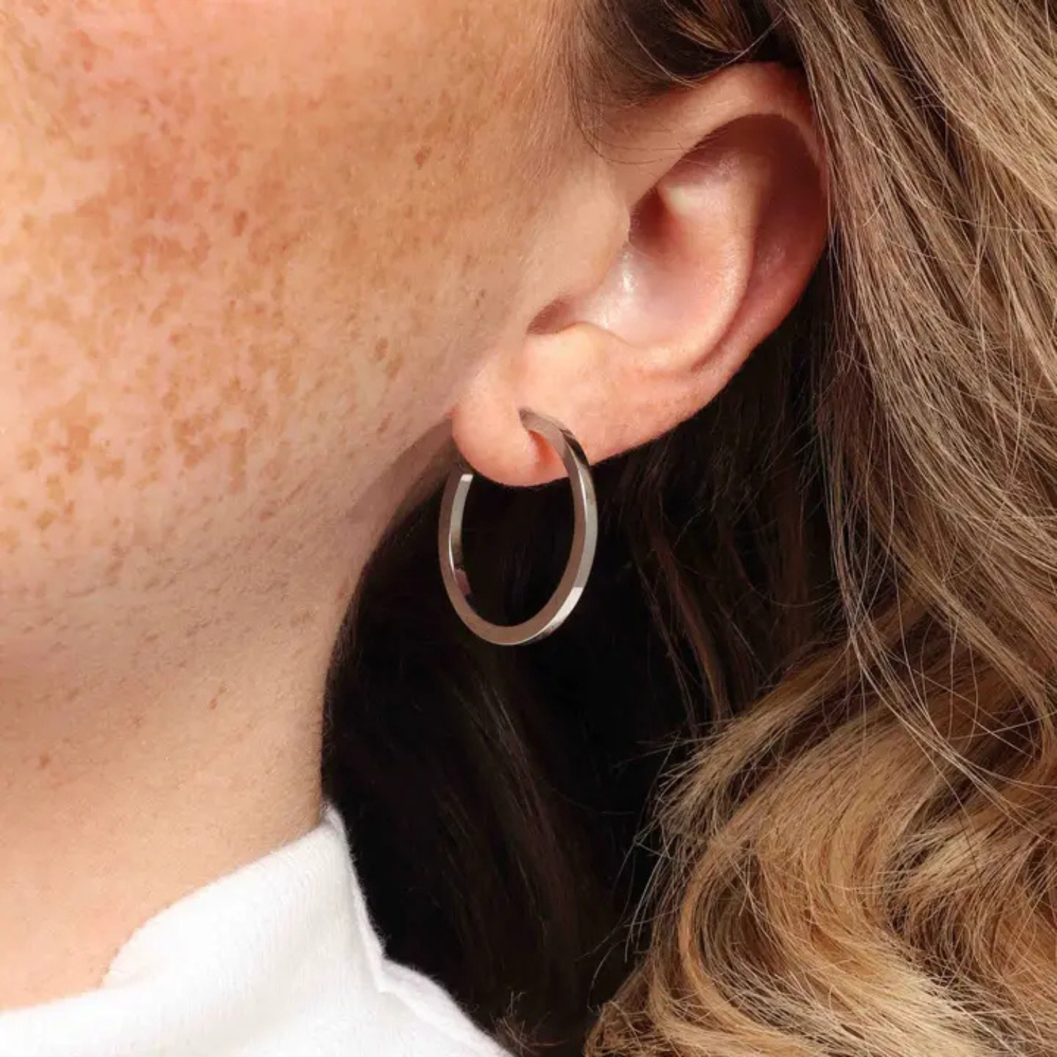 Model wearing a silver 1-inch hoop earring by Marrin Costello on pierced ear