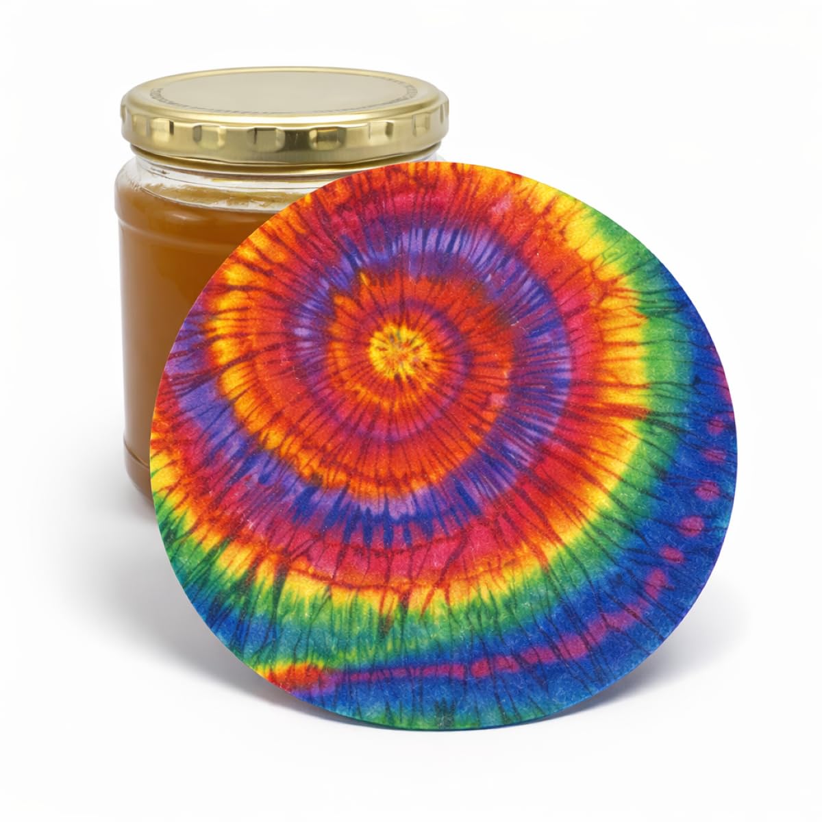 Tie-dye rainbow patterned silicone jar opener leaning against a honey jar on white background