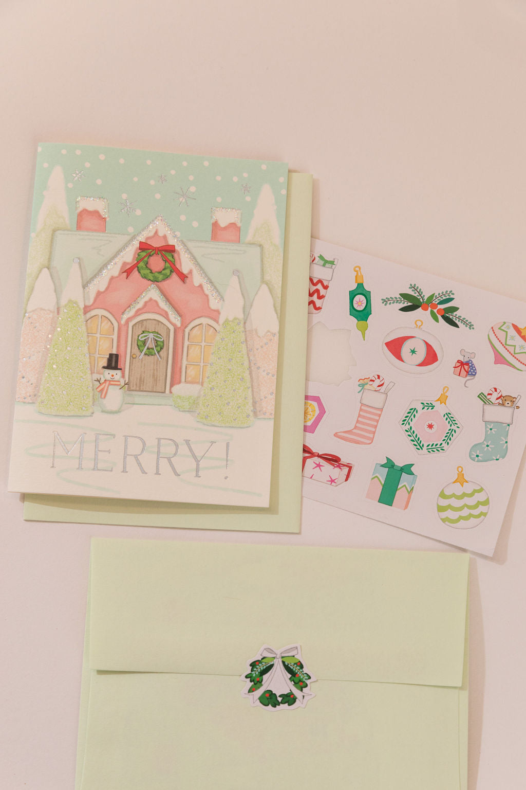 Merry House greeting card with snowman and pink cottage, shown with sticker sheet and mint envelope