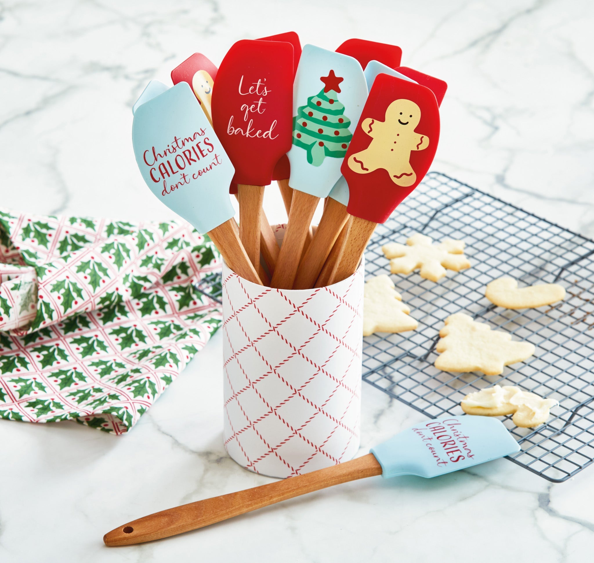 Assorted Christmas silicone spatulas with holiday designs in a festive ceramic crock