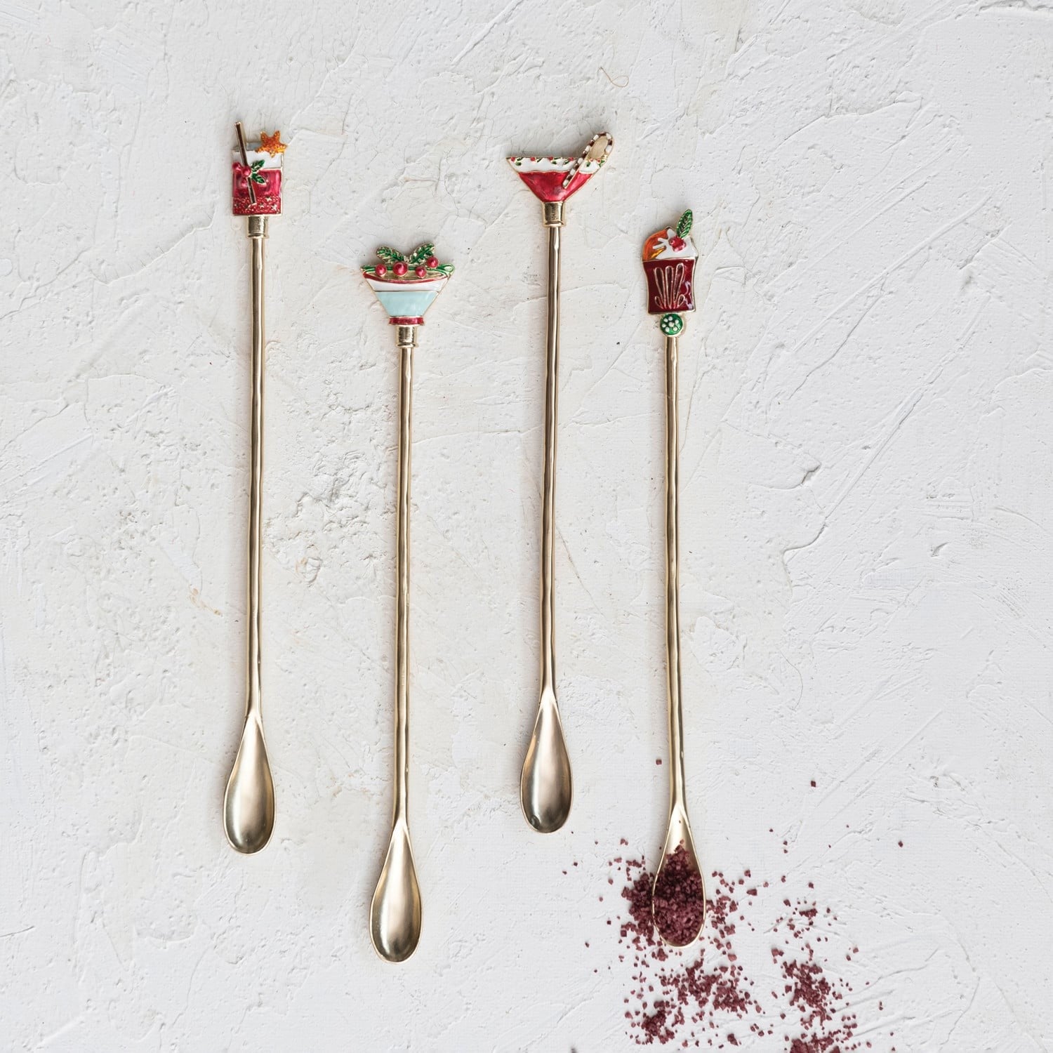 Set of four gold holiday cocktail spoons with colorful Christmas-themed enamel decorative tops