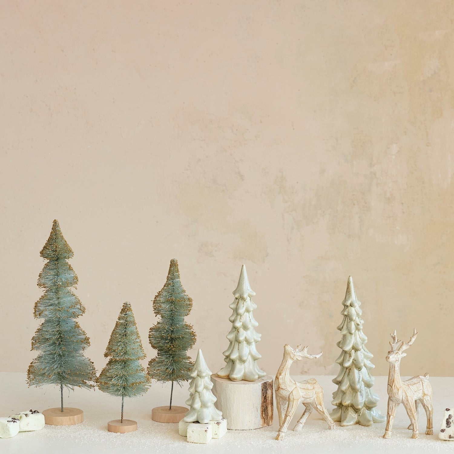Ivory stoneware Christmas tree figurines styled with bottle brush trees and reindeer decorations