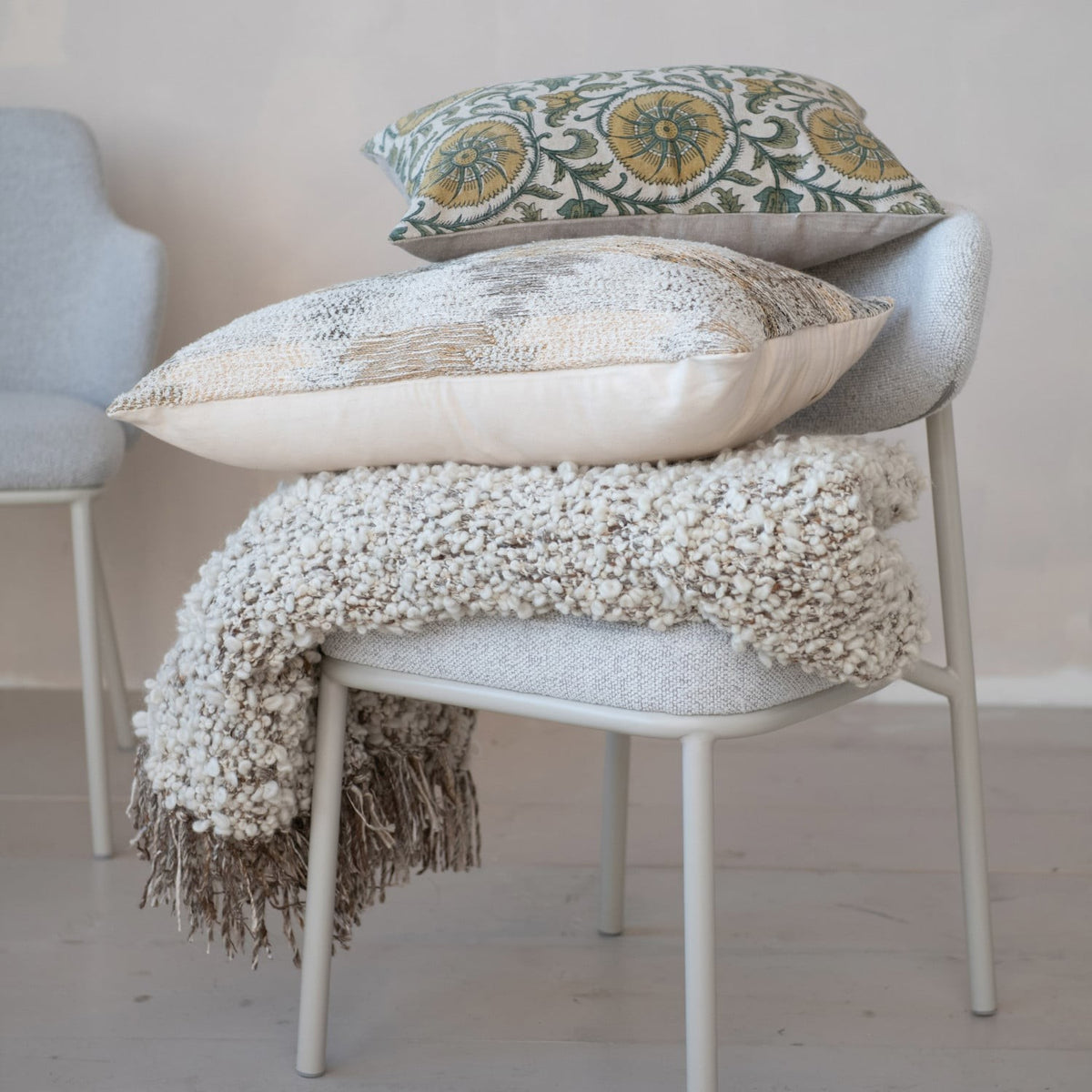 Chunky woven wool blend shag throw draped over a light gray chair with decorative pillows