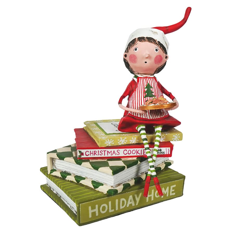 Lori Mitchell elf figurine sitting on stacked Christmas books holding cookie tray